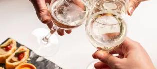 wine glasses clink in cheers, above a platter of pinchos