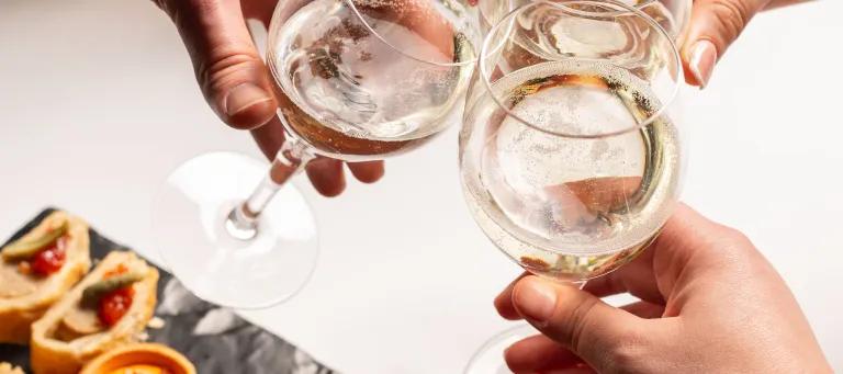 wine glasses clink in cheers, above a platter of pinchos